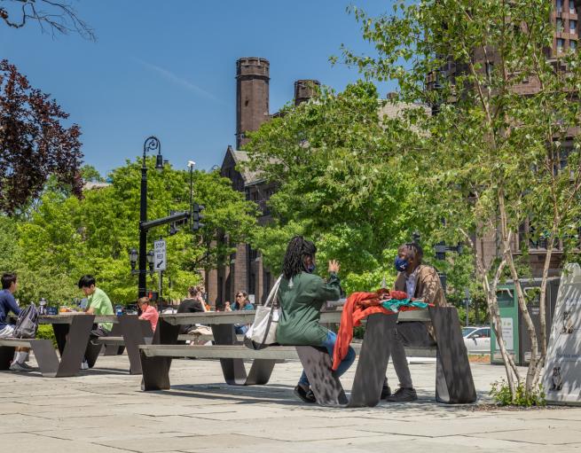 Students sitting at picnic table near School of Public Health