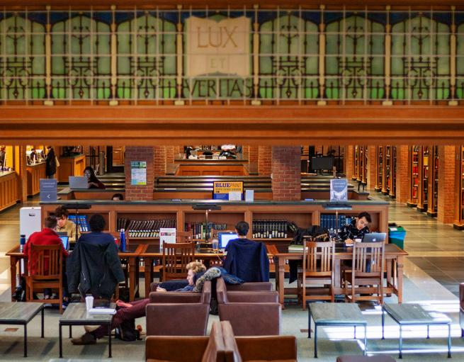 Students study at tables inside Bass Library