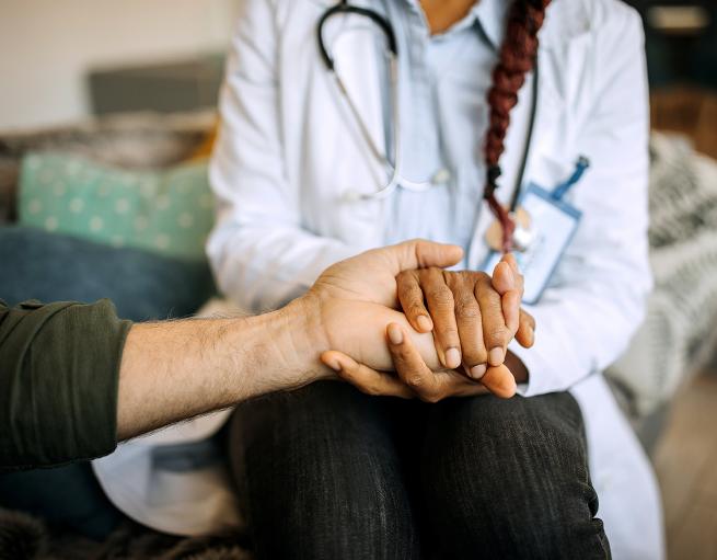 A nurse holds her patient's hand