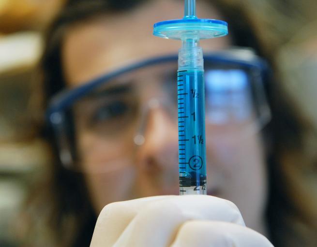 Scientist examining a syringe
