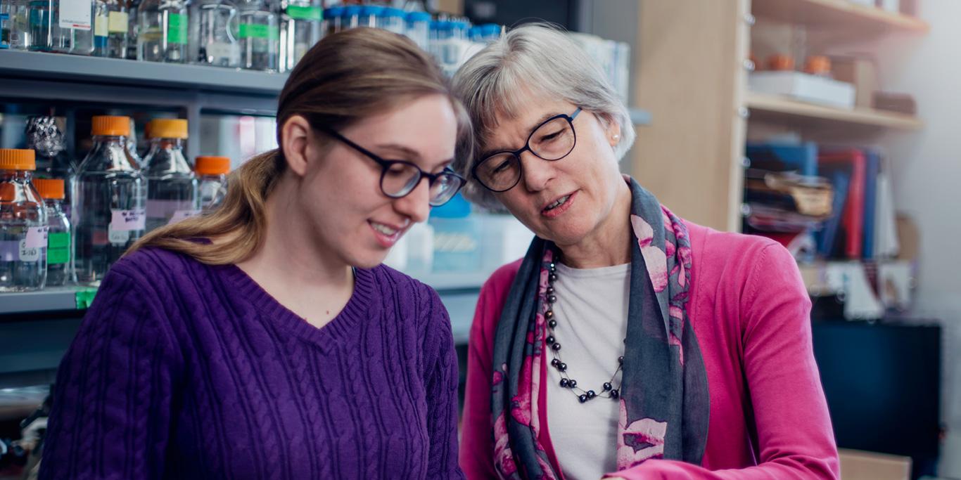 Dean Lynn Cooley looking on a computer with student