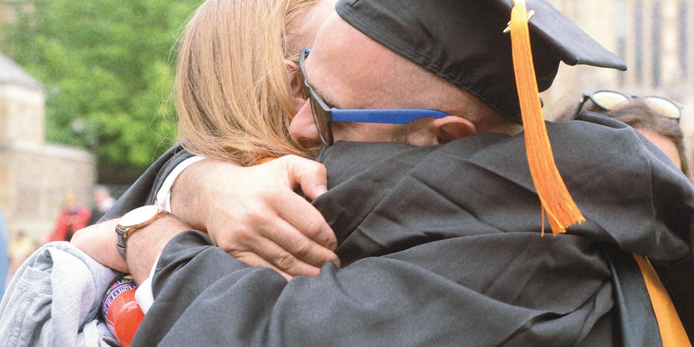 A student hugging their parent on graduation