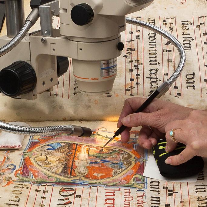 A conservator uses specialized tools to treat a medieval missal