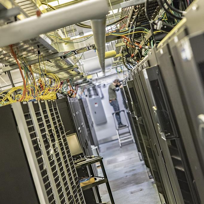 A person on a ladder inspects equipment in Yale's West Campus data center