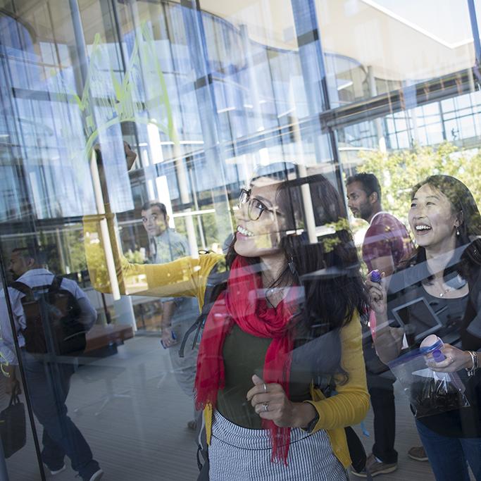 Students painting on the glass wall of the Yale School of Management building