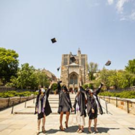 Graduates throw their caps in the air on Cross Campus
