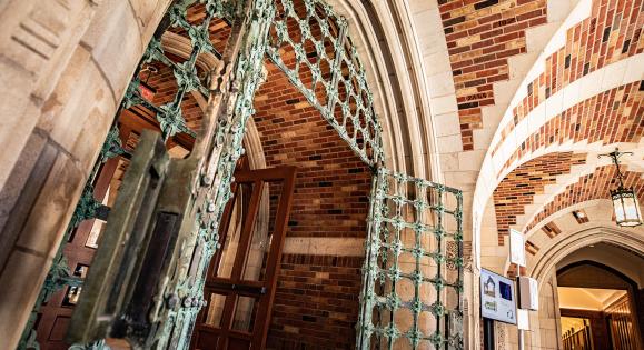 A green gate and brick archways in the Humanities Quadrangle