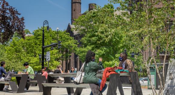 Students sitting at picnic table near School of Public Health