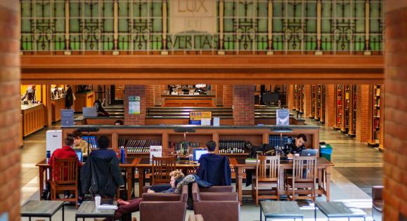 Students study at tables inside Bass Library