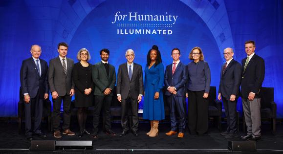 Presenters pose for a group photograph on stage at For Humanity Illuminated in Boston
