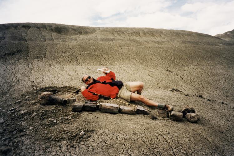 Coleman Burke lying down next to a dinosaur bone in Patagonia